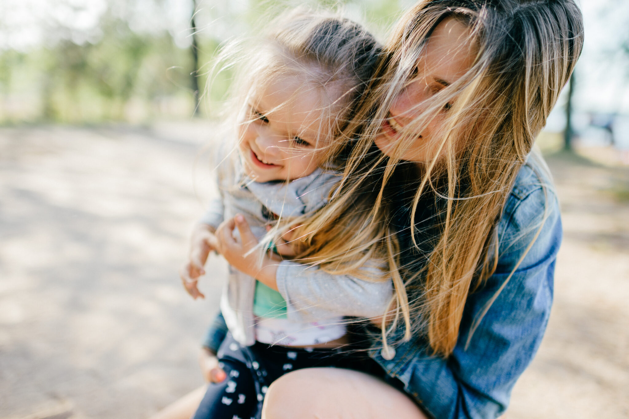 Happy smiling mother hugging her lovely little daughter outdoor.